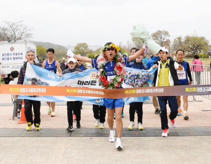 태화강 국제마라톤대회에서 풀코스 100회를 달성한 배상국씨가 동료들의 환호를 받으며 골인하고 있다.