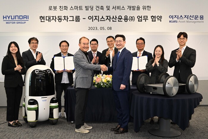 현대차∙기아의 실내외 배송 로봇(왼쪽)과 모베드(MobED, 오른쪽)가 놓인 가운데 현대차∙기아 연구개발본부장 김용화 부사장(앞줄 왼쪽)과 이지스자산운용 리얼에셋부문 정석우 대표(앞줄 오른쪽)가 기념 사진을 촬영하는 모습. 사진제공=현대차그룹