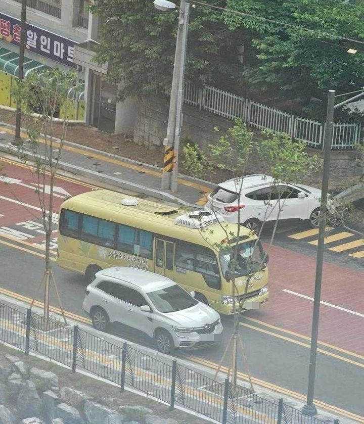 갓길에 주차된 차량을 피해 중앙선을 넘나들며 주행하는 버스.
