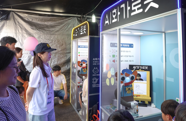 2025 울산고래축제가 열리고 있는 지난 27일 과학체험존 부스를 찾은 관람객들이 AI 화가 로봇이 그려주는 인물화 체험을 하고 있다. 이수화 기자