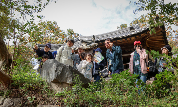 '2025 반구천의 암각화 선사문화 탐방'에 참여한 조별 참가자들이 집청정 앞에서 반구를 살펴보며 울산시 문화관광해설사의 설명을 듣고 있다. 이수화 기자