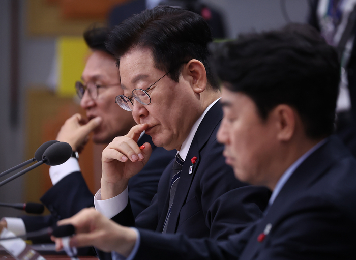 이재명 대통령이 19일 정부서울청사 별관에서 열린 금융위원회·공정거래위원회 업무보고에서 자료를 살펴보고 있다. 왼쪽부터 김민석 국무총리, 이재명 대통령, 강훈식 대통령 비서실장. 연합뉴스