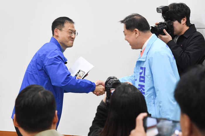 3월 25일 울산시의회 프레스센터에서 더불어민주당 김상욱 의원(왼쪽)과 진보당 김종훈 전 동구청장이 우연히 만나 악수하고 있다. 울산시의회 제공