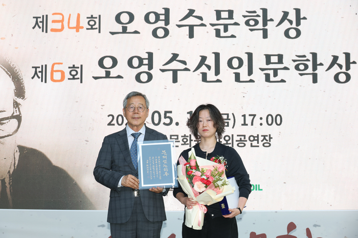 도홍진 전 울산과학대 교수가 황정은 제34회 오영수문학상 수상자에게 수상작 ‘문제없는, 하루’의 내용을 담은 휘호를 전달하고 기념촬영을 하고 있다. 이수화 기자