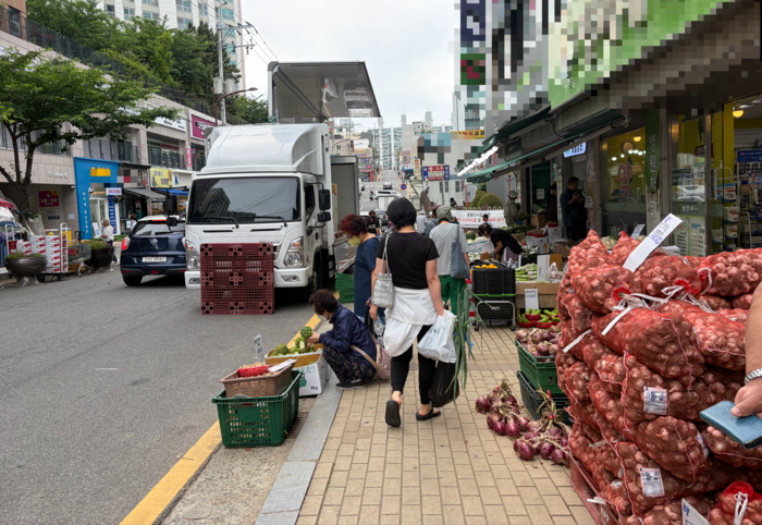 울산 동울산시장이 일부 자율 정비에도 불구하고 인도 점유 영업이 이어지면서 보행권과 생계권 사이의 갈등이 계속되고 있다. 사진은 동울산시장 인근의 인도에 불법 적치물이 쎃여 있어 보행자가 불변을 겪고 있는 모습.
