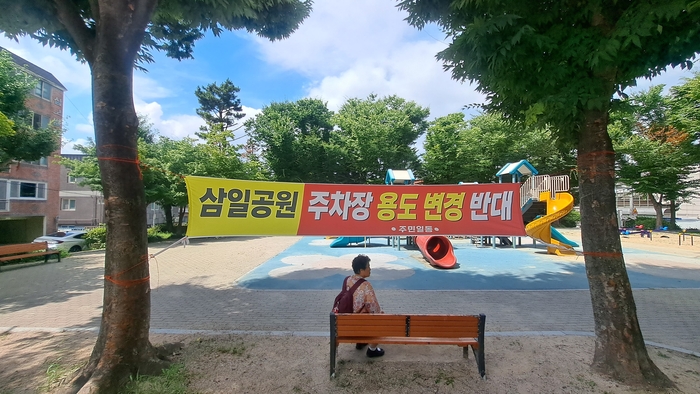 울산 중구 병영2동에 위치한 삼일공원 입구에 주차장 조성을 반대하는 내용의 현수막이 설치돼 있다.
