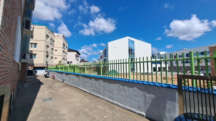 학성초등학교와 인전한 사유지 경계부에 학교에서 세운 녹색 철조망과 사유지 토지주들이 설치한 돌담벽이 바짝 붙어 있다.