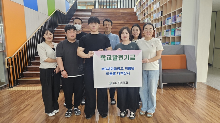 옥성초 김영신 교장이 12일 엠지(MG)새마을금고 씨름단 소속 이용훈 선수(앞줄 왼쪽에서 세번째)에게 학교발전기금을 전달받고 교직원들과 기념사진을 찍고있다. 울산교육청 제공